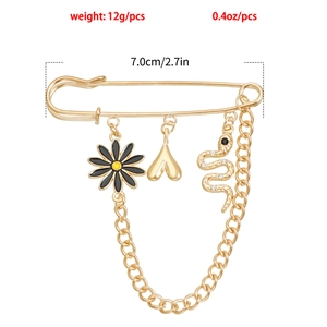 Détail de la broche épingle vintage dorée avec pendentifs serpent, fleur et cœur