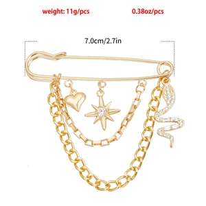 Détail d'une épingle dorée vintage avec breloques cœur, serpent, étoile et chaînes