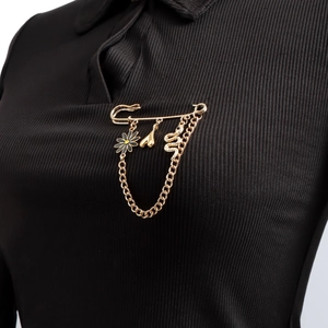 Broche vintage dorée avec pendentifs serpent et marguerite sur un vêtement noir