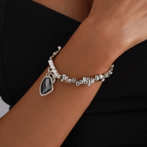 Silbernes Perlenarmband mit facettiertem schwarzem Anhänger am Handgelenk gezeigt