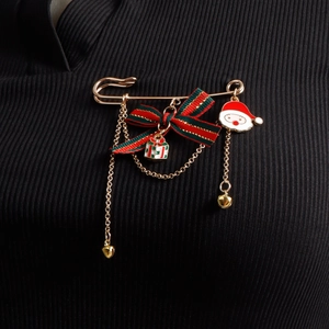 Detail of Christmas bow brooch with Santa charm and gold chains on black knit fabric