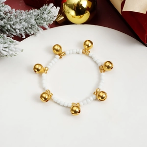 Bracciale natalizio di perle con campanelli dorati su sfondo festivo rosso e bianco