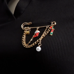 Detail of Christmas brooch with gold chains, bells, stockings and candy cane on black fabric