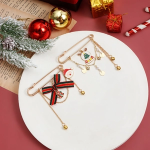 Close-up of golden Christmas brooches with festive bow and tree charms on a tray
