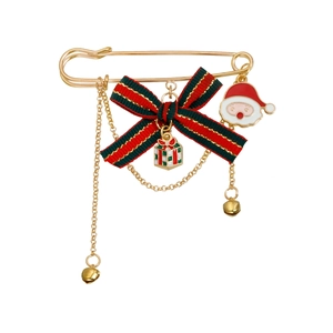 Detail of Christmas brooch with festive ribbon bow, golden bells, and Santa Claus pendant