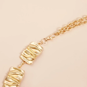 Detailed shot of golden irregular geometric wavy metal plates on a slim waist chain belt