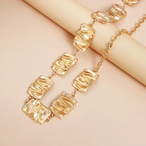 Macro detail of golden geometric metal waist chain with elegant pleated texture links