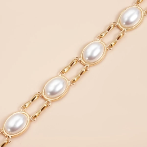 Detailed macro view of vintage gold chain with large oval pearls and beaded metal edges