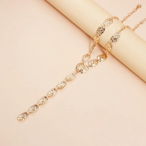 Close-up of golden Y-shaped necklace featuring hammered irregular leaf-like metal charms