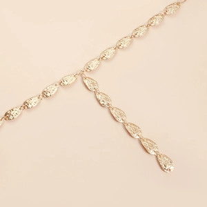 Detail view of gold hammered leaf y-shaped body chain with smooth metallic finish