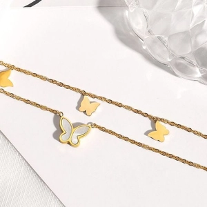 Detailed macro view of 18k gold butterfly anklet with white shell inlay and cross chain