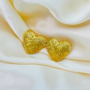 Elegante 18k vergoldete Herzohrringe mit strukturierter Oberfläche auf weißer Seide