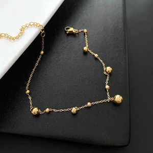 Polished gold minimalist ball anklet with lobster clasp on minimalist background