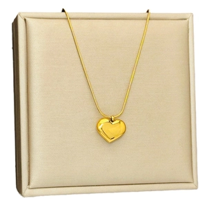 Elegant 18k gold heart pendant necklace on beige jewelry display stand