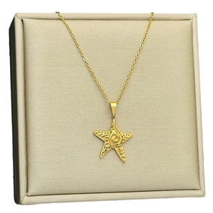 Élégant collier pendentif étoile de mer dorée avec texture sur fond de soie lisse