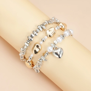 Détail d'un ensemble de trois bracelets superposés avec pendentif cœur et perles