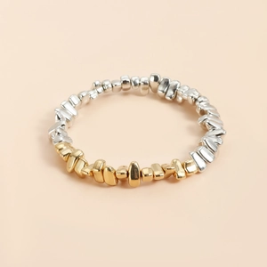 Vue macro d'un bracelet de perles irrégulières dorées et argentées à effet miroir