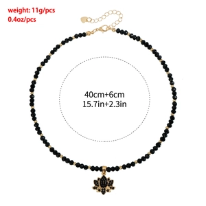 Détail du collier à perles avec perles noires et pendentif lotus doré orné de cristaux