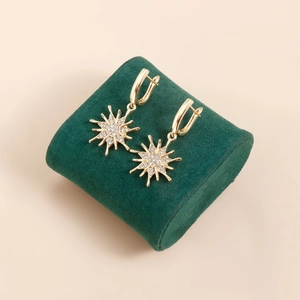 Nahaufnahme der goldenen Sonnenblumen-Ohrringe mit glitzernden Steinen auf Samtständer