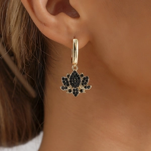 Boucles d'oreilles lotus dorées avec pavé de zircons noirs portées par un mannequin