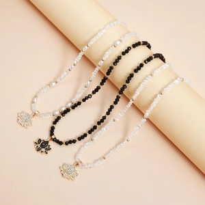 Détail de colliers perlés avec pendentifs lotus en cristal étincelant en noir et blanc
