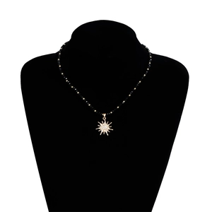Detailansicht der schwarzen Perlenkette mit einem funkelnden goldenen Sonnenstern-Anhänger