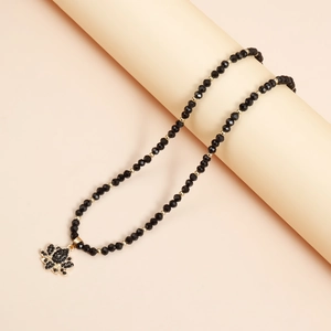 Détail du collier de perles avec pendentif lotus en cristal noir et accents dorés