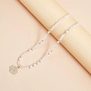 Gros plan d'un pendentif lotus doré avec strass sur un collier de perles blanches