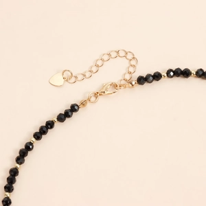 Vue détaillée du collier en perles noires avec fermoir mousqueton doré et pendentif cœur