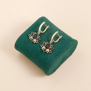 Détail de boucles d'oreilles lotus avec cristaux noirs sur un support en velours