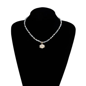 Gros plan du collier de perles et cristaux avec pendentif fleur de lotus scintillant