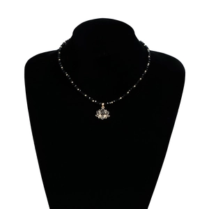 Détail du collier de perles avec un pendentif lotus doré serti de cristal noir sur buste