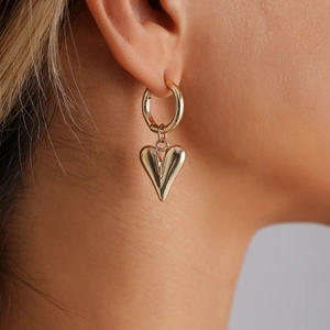 Close-up of a gold heart hoop earring worn by a model with a polished mirror finish