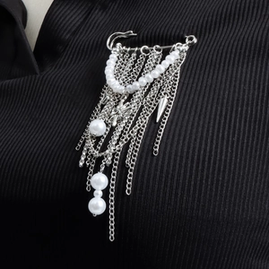 Broche à franges argentées avec perles et glands métalliques épinglée sur tissu noir