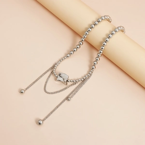Detail of silver irregular metal pendant on beaded ball chain with minimalist aesthetic