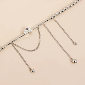 Macro shot of silver beaded chain with abstract geometric pendant and hanging tassels
