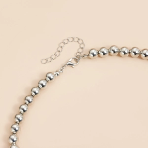 Detailed macro view of silver beaded necklace with adjustable lobster clasp and extension chain