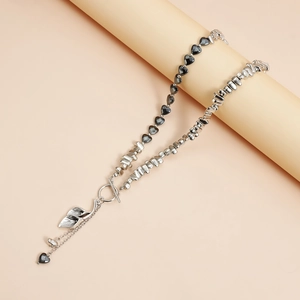Detail van kralenketting met hart, zilveren bladeren en OT-sluiting op een voetstuk