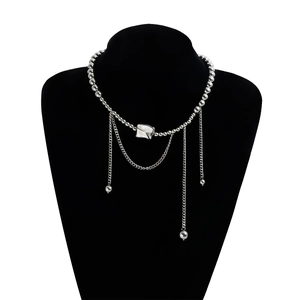 Close-up of silver geometric necklace featuring a wrinkled pendant and long chain tassels