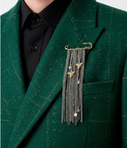 Dettaglio di una spilla vintage con frange, api e stelle su abito in tweed