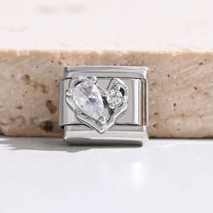 Makroaufnahme von Silber-Charm mit hohlem Herzdesign und birnenförmigen Zirkonia