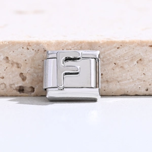 Makro-Detail des silbernen Edelstahl-Charm-Links mit geprägtem Buchstaben F für Armbänder