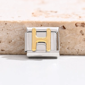 Detail of Italian charm bracelet link with a golden letter H in stainless steel