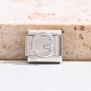 Makro-Detail des italienischen Charm-Glieds aus silbernem Edelstahl mit geprägtem G