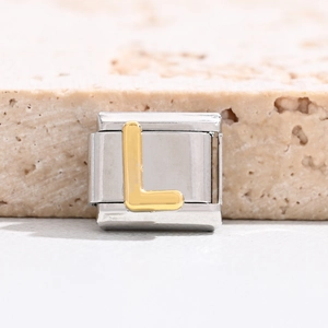 Macro detail of Italian charm bracelet link with gold 3D letter L on steel base