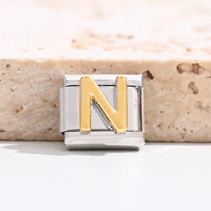 Macro view of gold letter N Italian charm link made of polished stainless steel