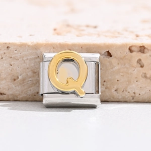 Macro detail of Italian charm link featuring a golden relief letter Q on stainless steel