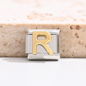 Detailed macro view of an Italian charm bracelet link with a gold-tone letter R on steel
