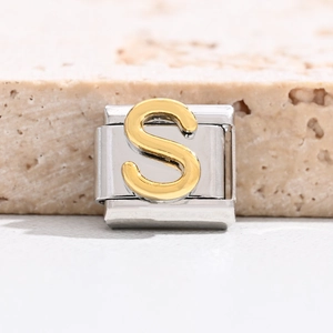 Macro shot of Italian charm link featuring a gold relief letter S on polished steel