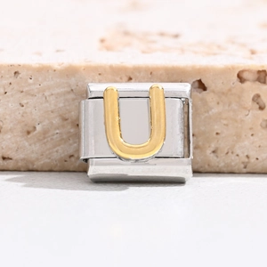 Macro shot of Italian charm bracelet link with gold-plated letter U on stainless steel base